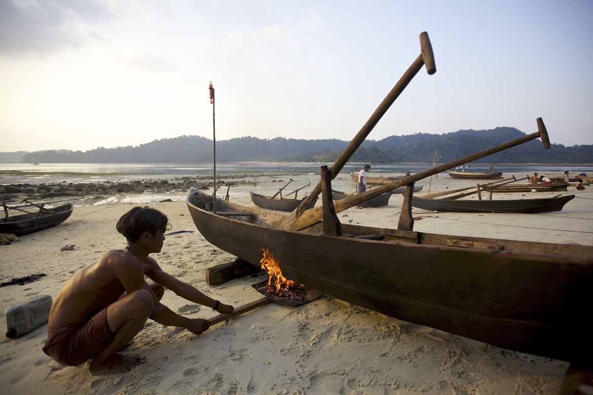 A Moken man works on his dugout canoe