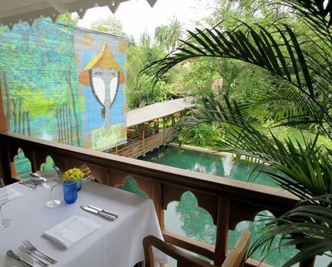 A dinner table overlooking a pond and artwork at Belmond Governor's Residence Yangon